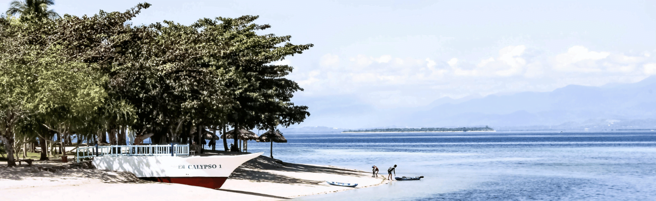 A boat parked on the shore of a beach.