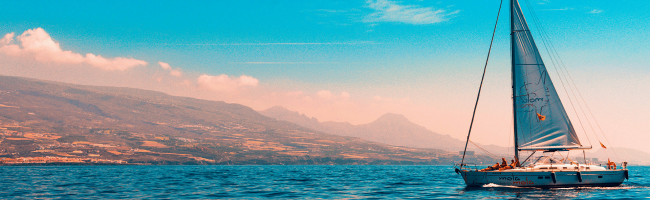 A charming sailboat drifting in the vast ocean, with soft waves lapping against its hull and a clear horizon ahead.